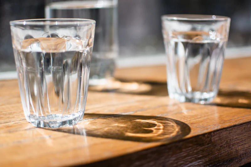 Two glasses of water on a wooden table illustrating hydration