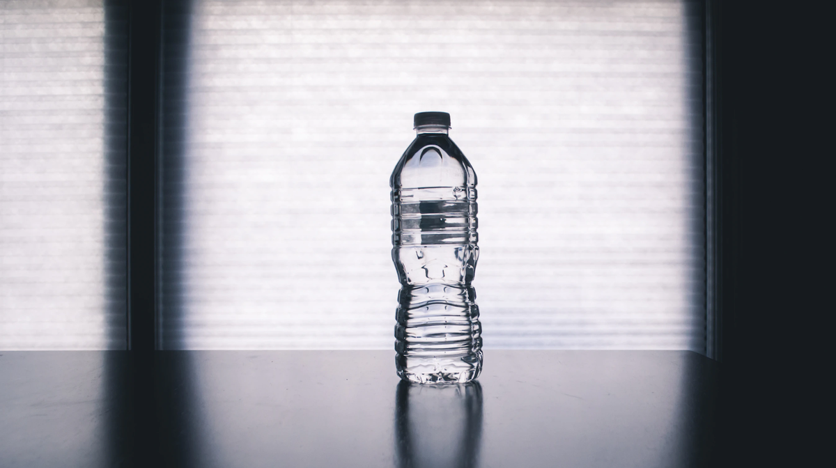 Plastic water bottle centered on a table with a window backdrop