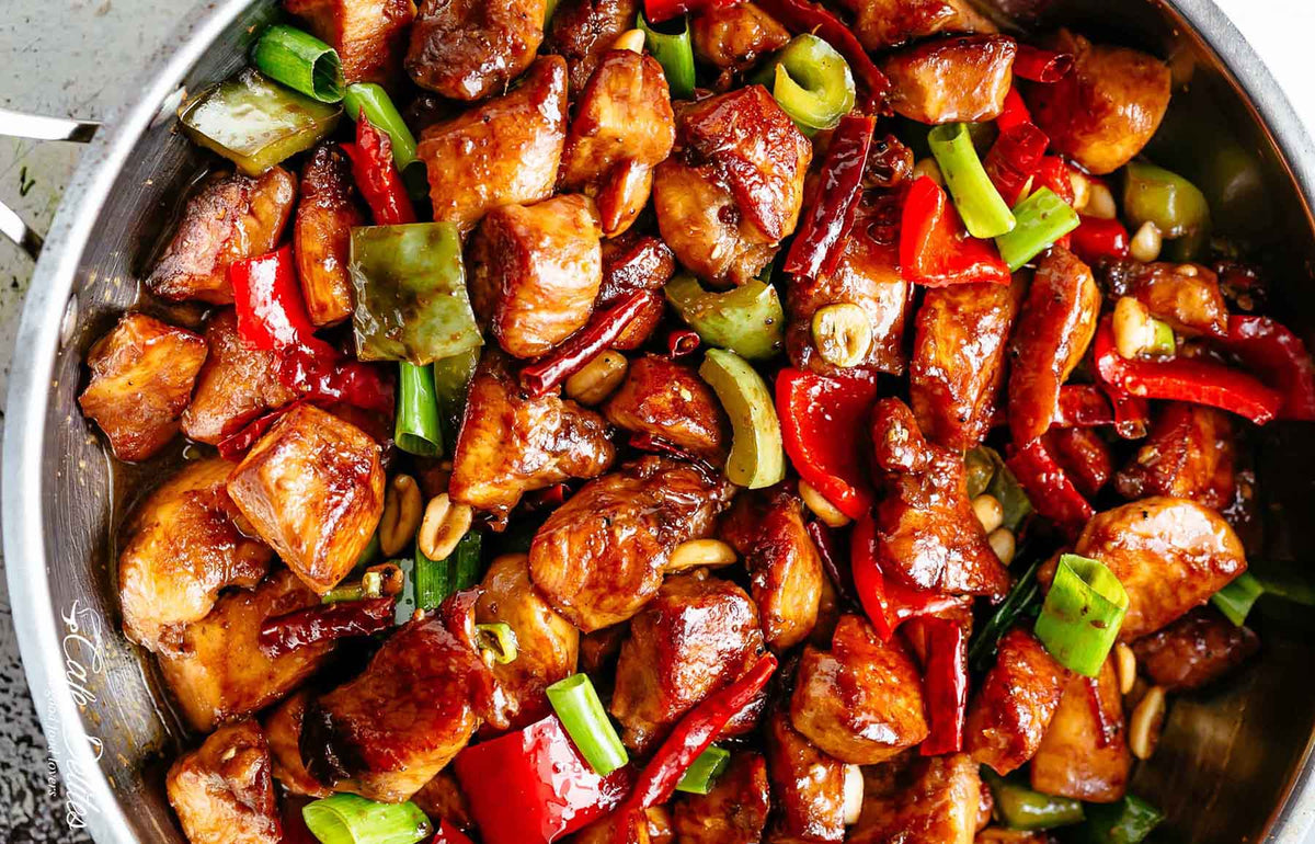 Stir fried kung pao chicken with peppers and green onions in a glossy sauce