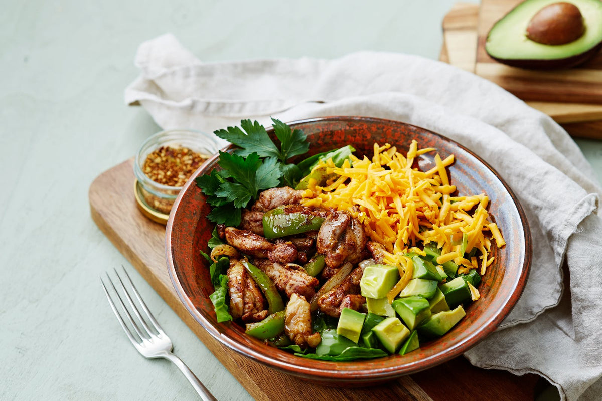 Chicken fajita bowl with grilled chicken avocado peppers greens and shredded cheese