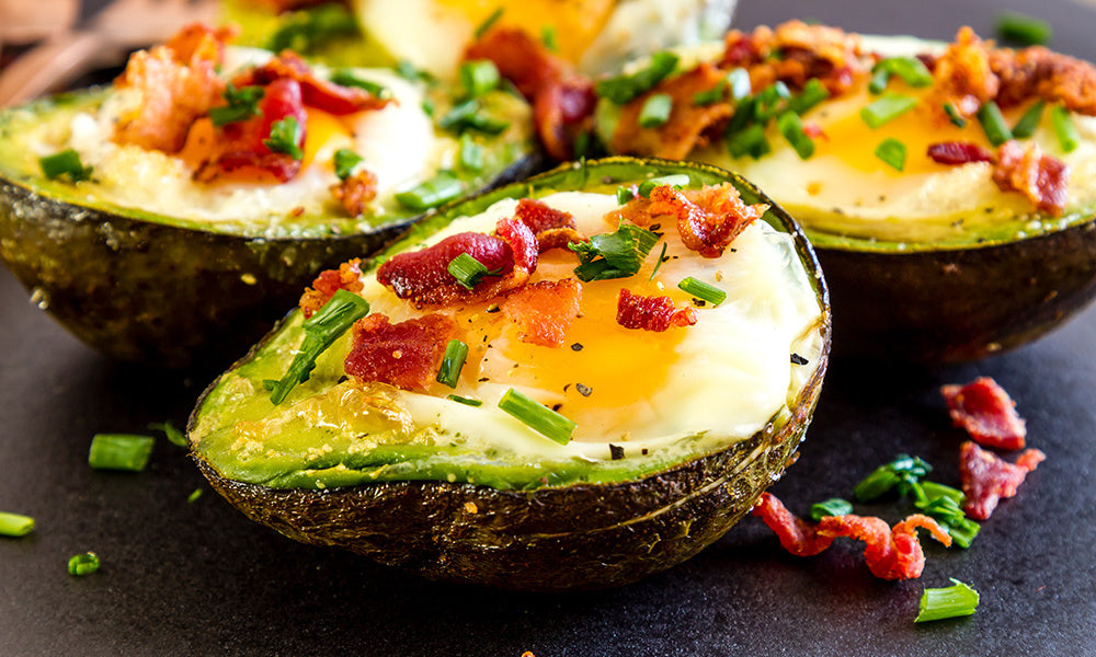 Avocado halves baked with eggs and crispy bacon bits topped with chives.