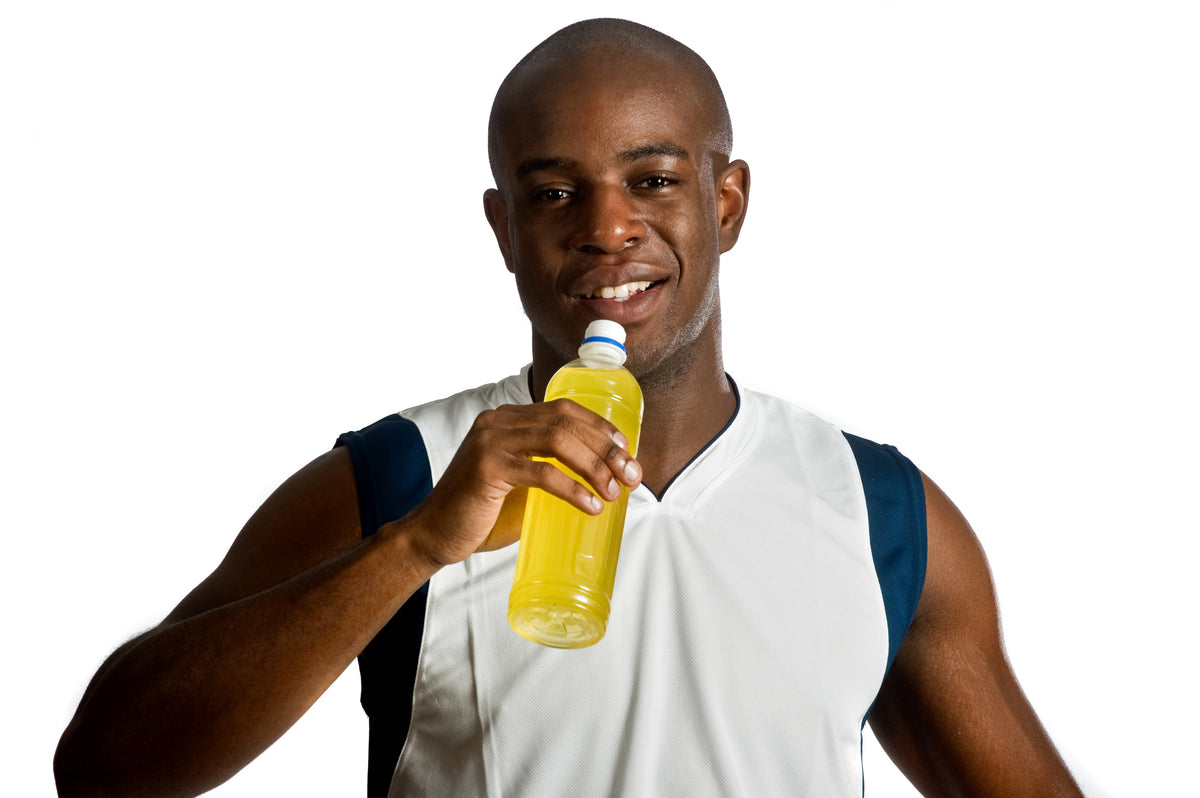 Athlete drinks yellow sports drink from a bottle against a white background
