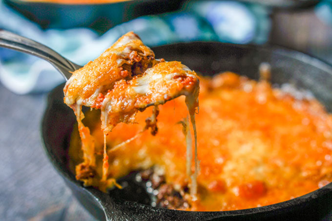 Keto chorizo cheese dip bubbling in a cast iron skillet with melted cheese being scooped
