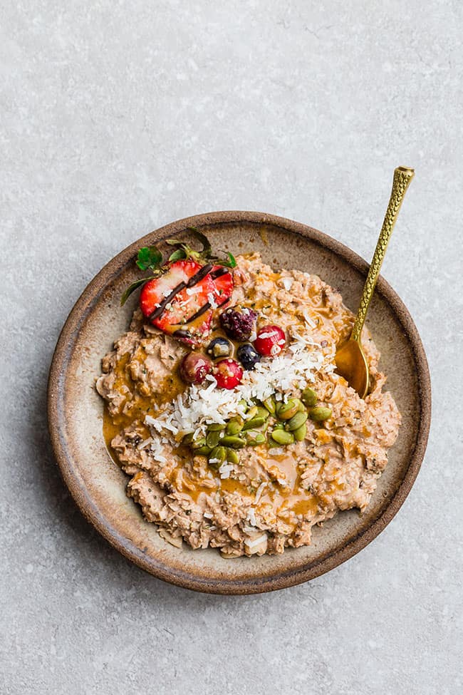 Keto porridge in a rustic bowl topped with coconut flakes berries and pistachios