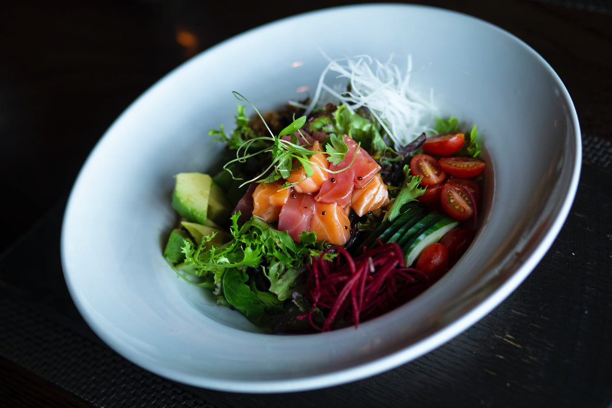 Bowl of fresh keto friendly salad with greens, cherry tomatoes and salmon