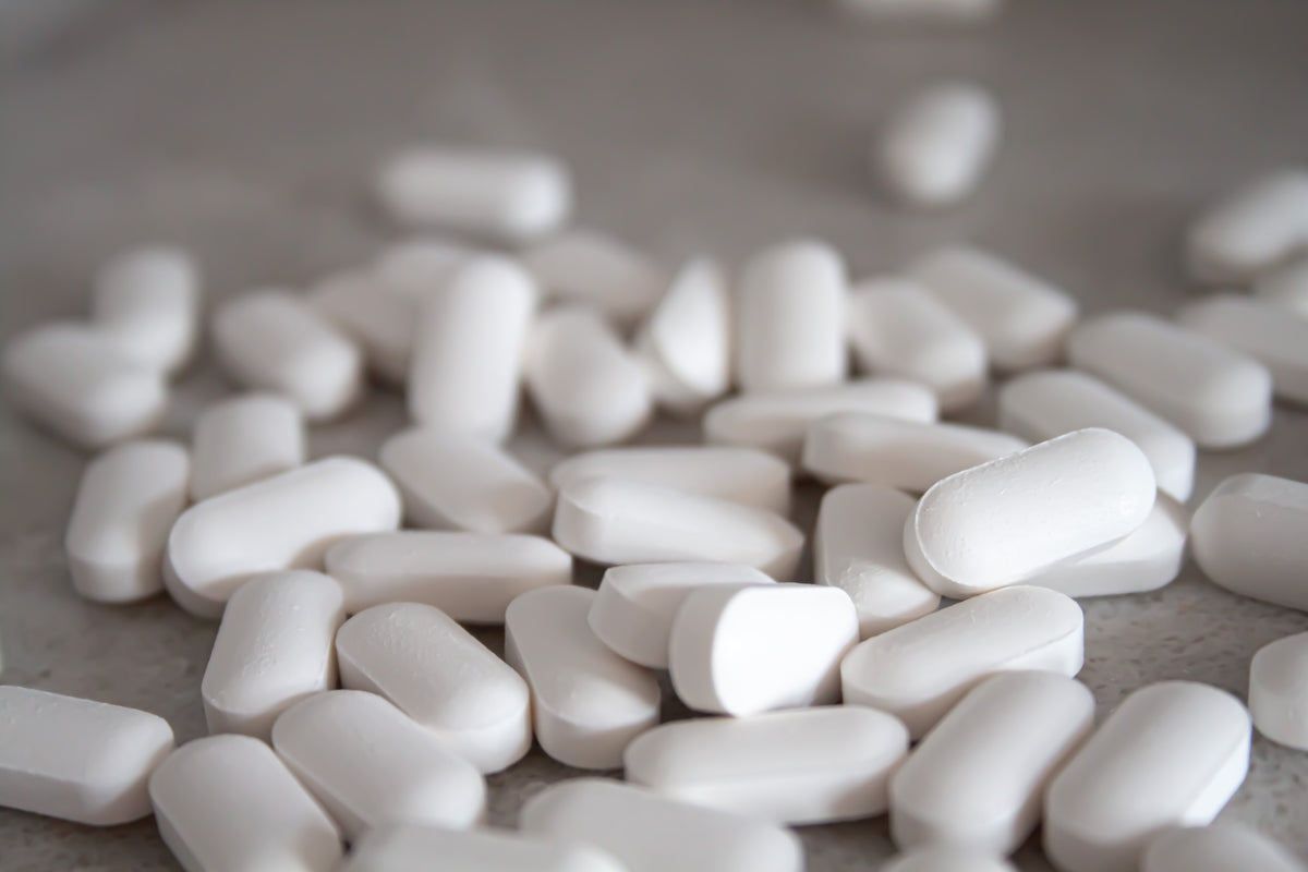 Close-up of white pills scattered on a neutral surface
