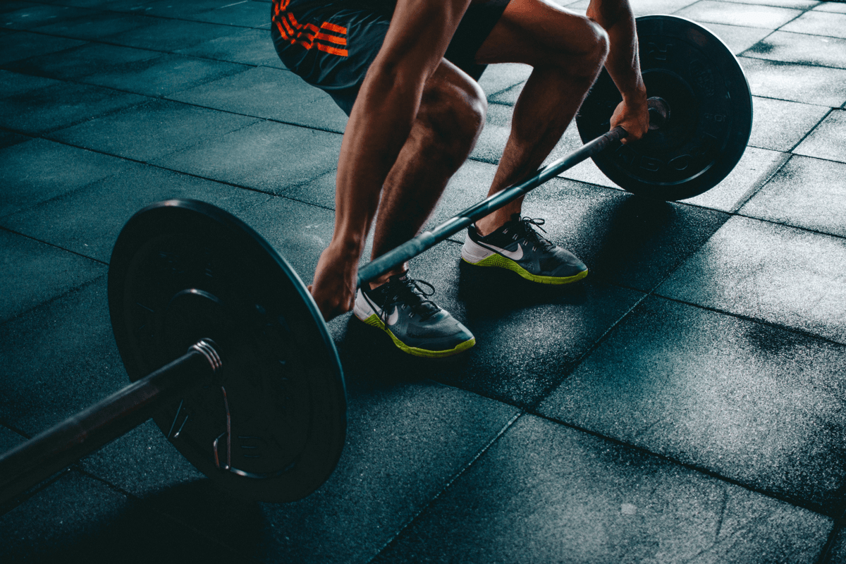 Athlete gripping a loaded barbell ready for a lift in a gym.