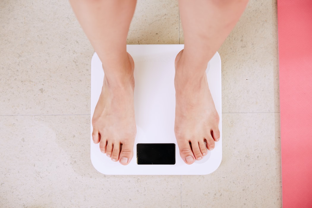 Top-down view of bare feet on a white digital bathroom scale